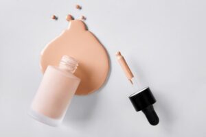 Mockup glass bottle of correction cosmetic product with pipette. Spilled Liquid foundation.